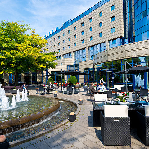 Terrace of the Maritim Hotel Bonn with seating areas, fountain, and guests dining and relaxing outdoors.