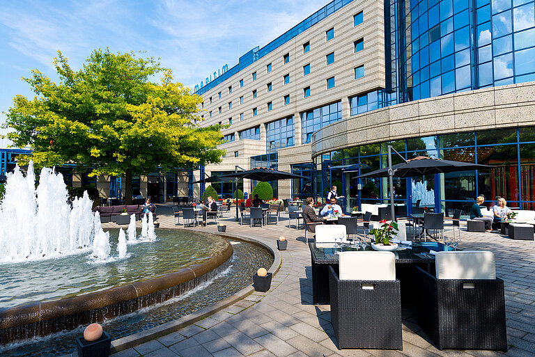 Terrace of the Maritim Hotel Bonn with seating areas, fountain, and guests dining and relaxing outdoors.