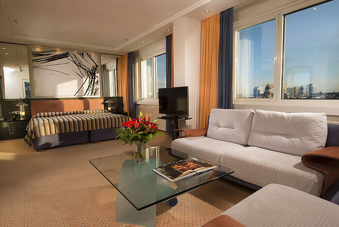 Kuckei Suite at Maritim proArte Hotel Berlin with sofa, glass coffee table, and large window overlooking Berlin skyline.