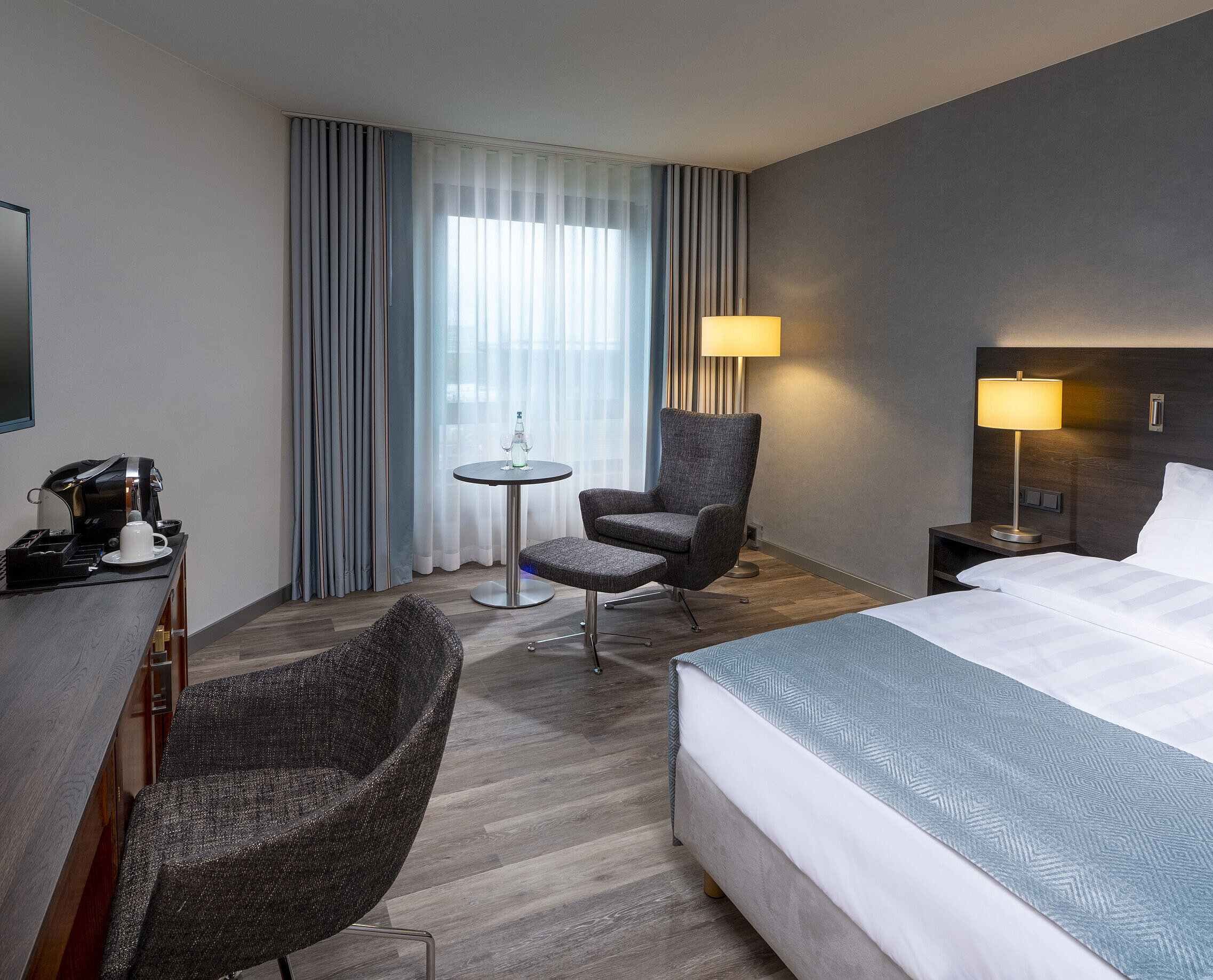 Modernly furnished Superior Queen room with desk, TV, seating area, and comfortable bed at Maritim Hotel Bremen.