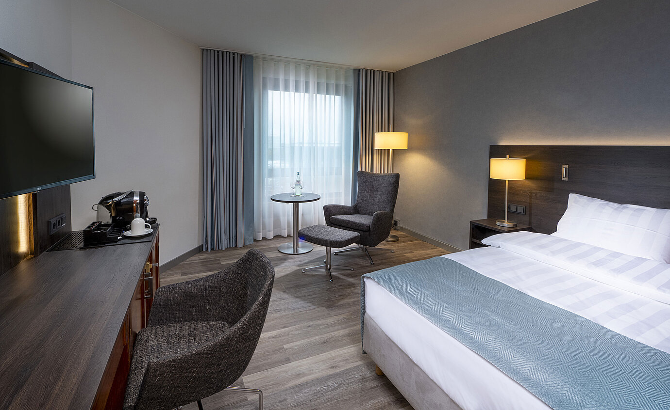 Modernly furnished Superior Queen room with desk, TV, seating area, and comfortable bed at Maritim Hotel Bremen.