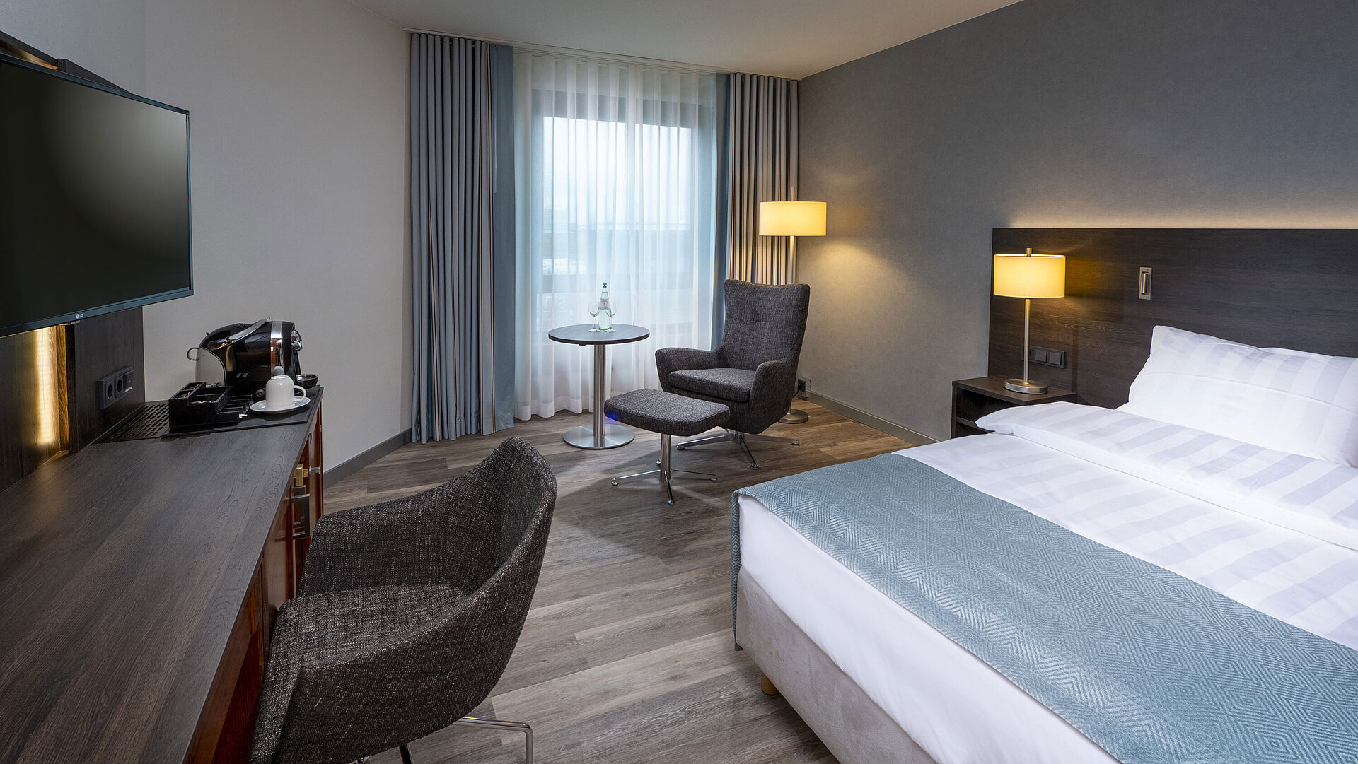 Modernly furnished Superior Queen room with desk, TV, seating area, and comfortable bed at Maritim Hotel Bremen.