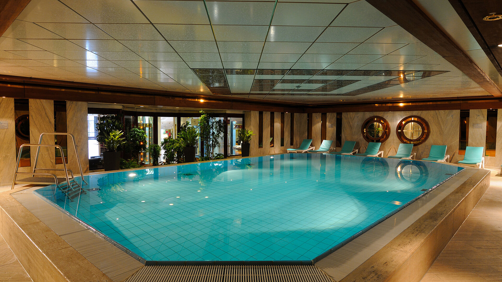 Indoor pool at Maritim Hotel Cologne with loungers and plants for a relaxing atmosphere.