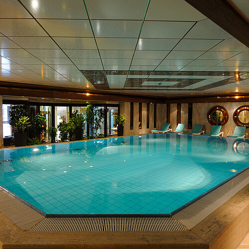 Indoor pool at Maritim Hotel Cologne with loungers and plants for a relaxing atmosphere.