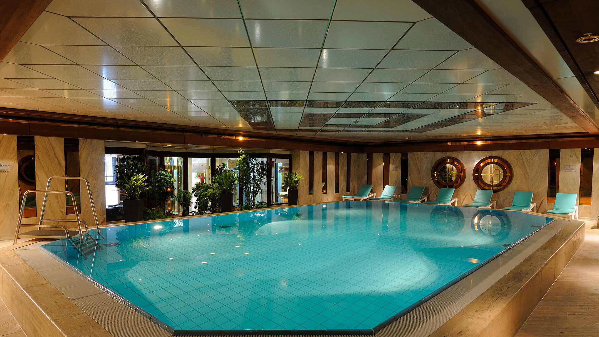Indoor pool at Maritim Hotel Cologne with loungers and plants for a relaxing atmosphere.