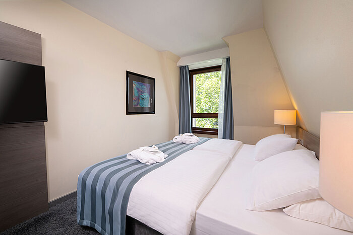 Bedroom of the Junior Suite at Maritim Hotel Königswinter with a double bed, window and bright interior.