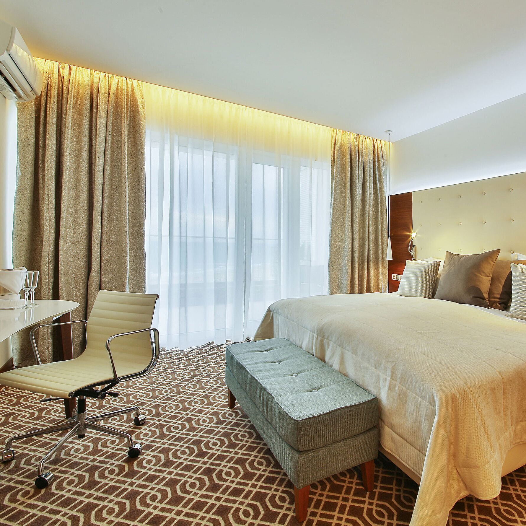 Modern hotel room with large bed, desk and warm lighting