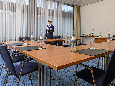 Meeting room with U-shaped seating and friendly Maritim staff member at Maritim Hotel Travemünde