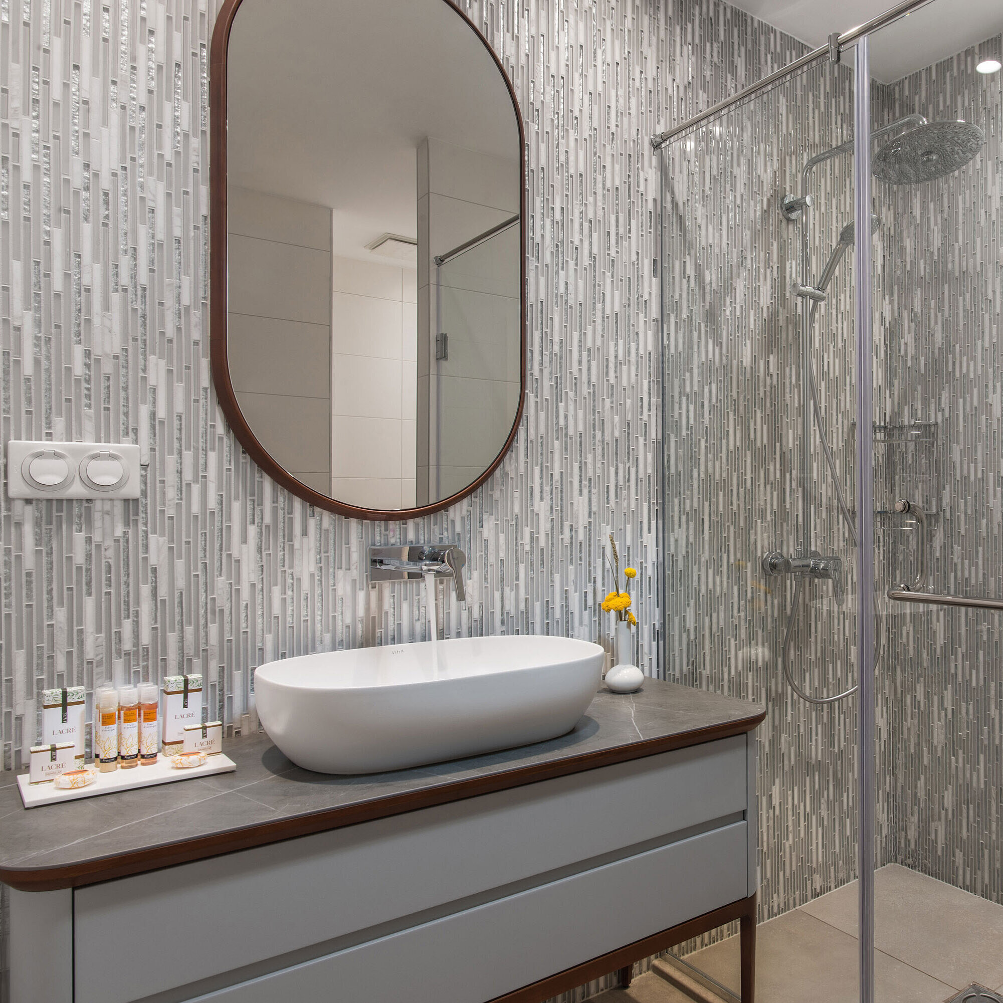 Modern bathroom at the Maritim Hotel Amelia with walk-in shower, grey mosaic wall, large mirror and stylish washbasin