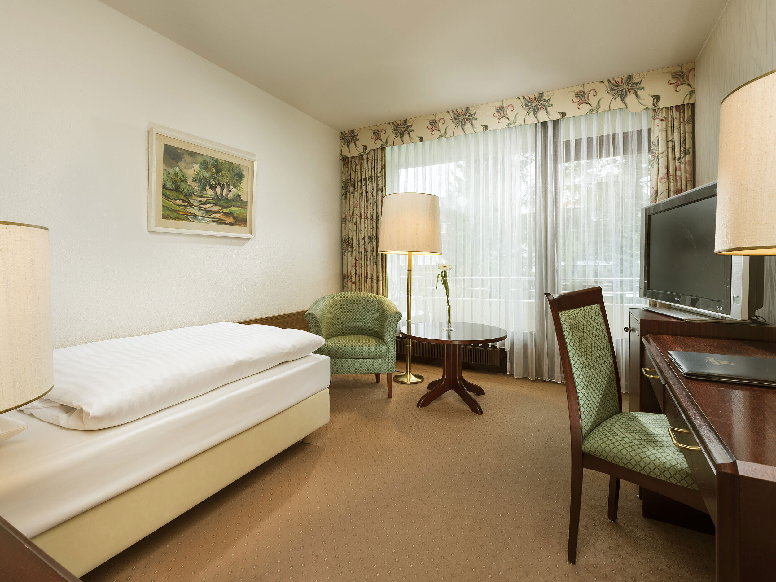 Single room with desk, armchair and balcony access at Maritim Hotel Bad Salzuflen