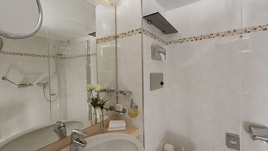 Bright bathroom at Maritim Hotel Bad Salzuflen with shower, large mirror and white tiles