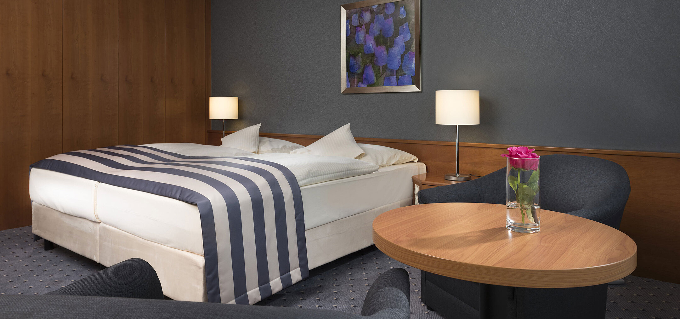 Cosy double room at Maritim Hotel Ulm with seating area, wooden wall and a fresh rose