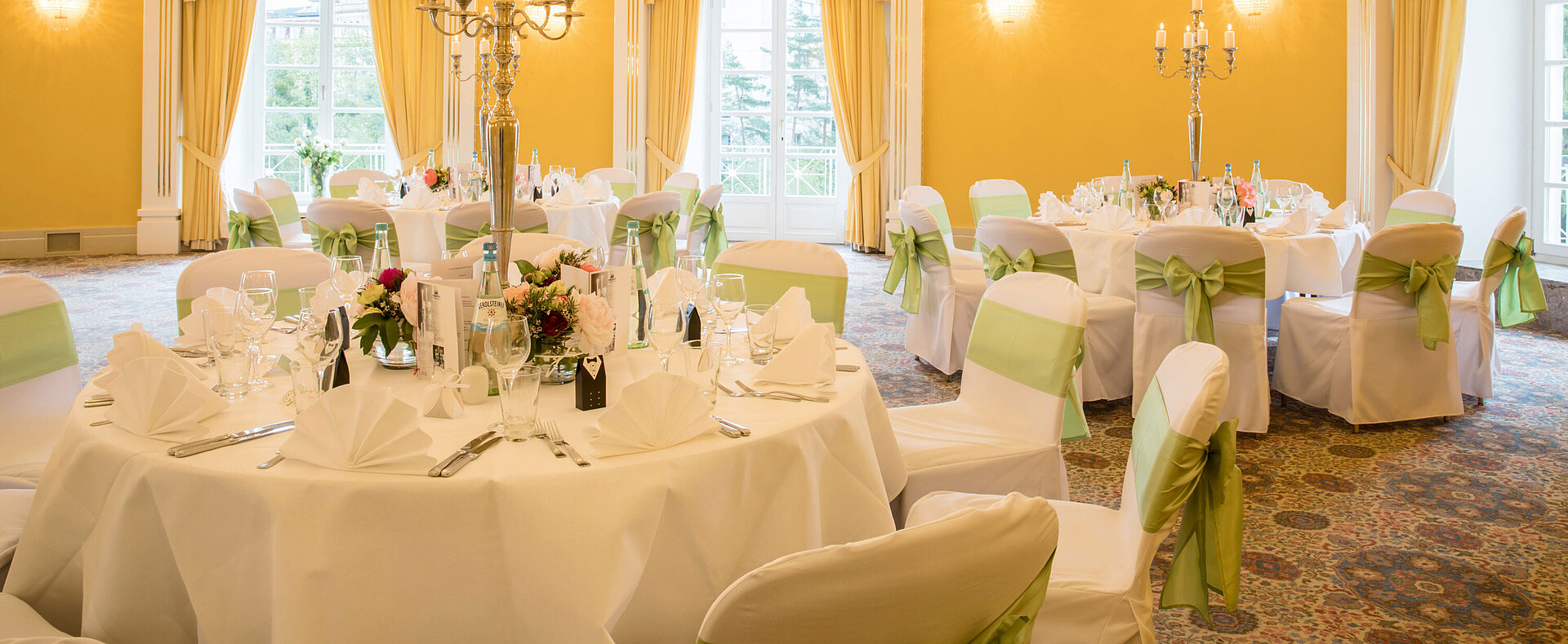 	Banquet hall with white covers and green bows for weddings at Maritim Hotel Bad Wildungen