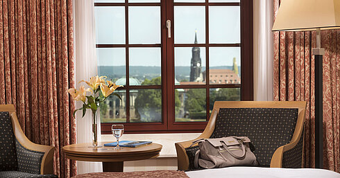 Seating area in the Superior room at Maritim Hotel Dresden with a window view of the historic old town.