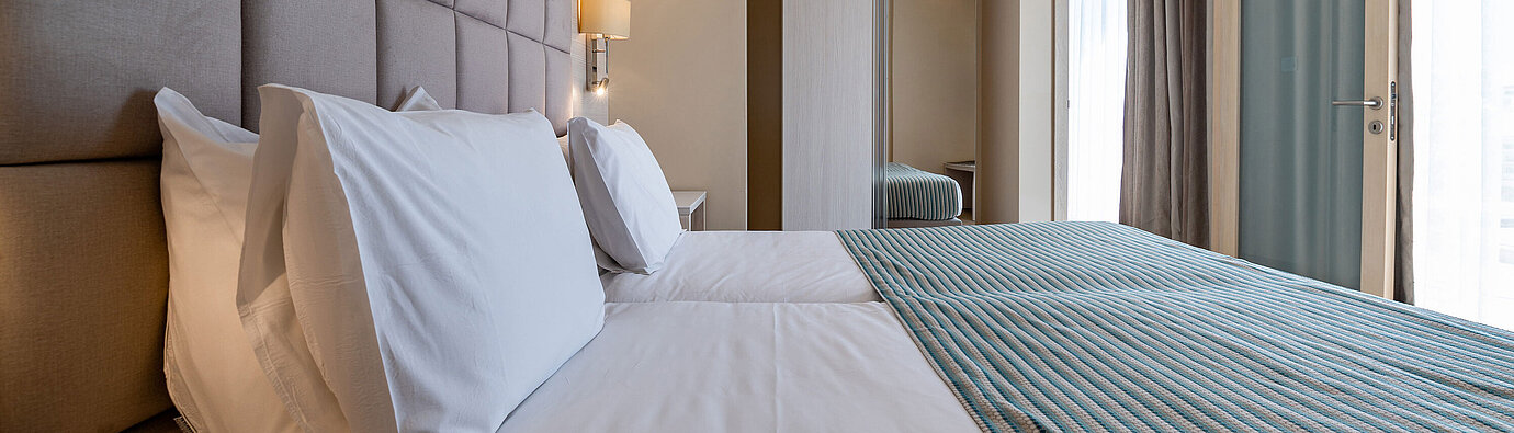 Stylish sleeping area in the Junior Suite at Maritim Antonine Hotel & Spa Malta featuring a comfortable double bed, upholstered headboard, modern wardrobe and floor-to-ceiling windows.