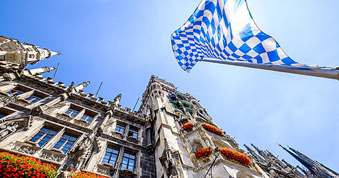 © fottoo - AdobeStock.com Bavarian flag above Marienplatz with historic town hall in Munich