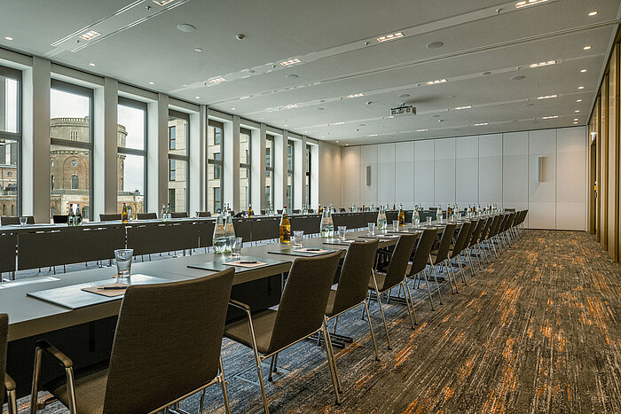 Modern meeting room at Maritim Hotel Ingolstadt with floor-to-ceiling windows, U-shape seating and professional setup.