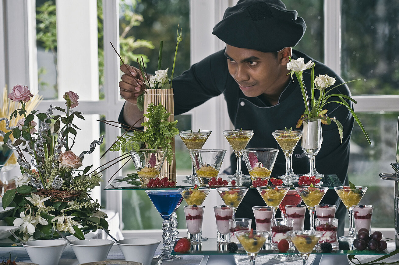Chef decorating artistic desserts and glasses at an elegant dessert buffet