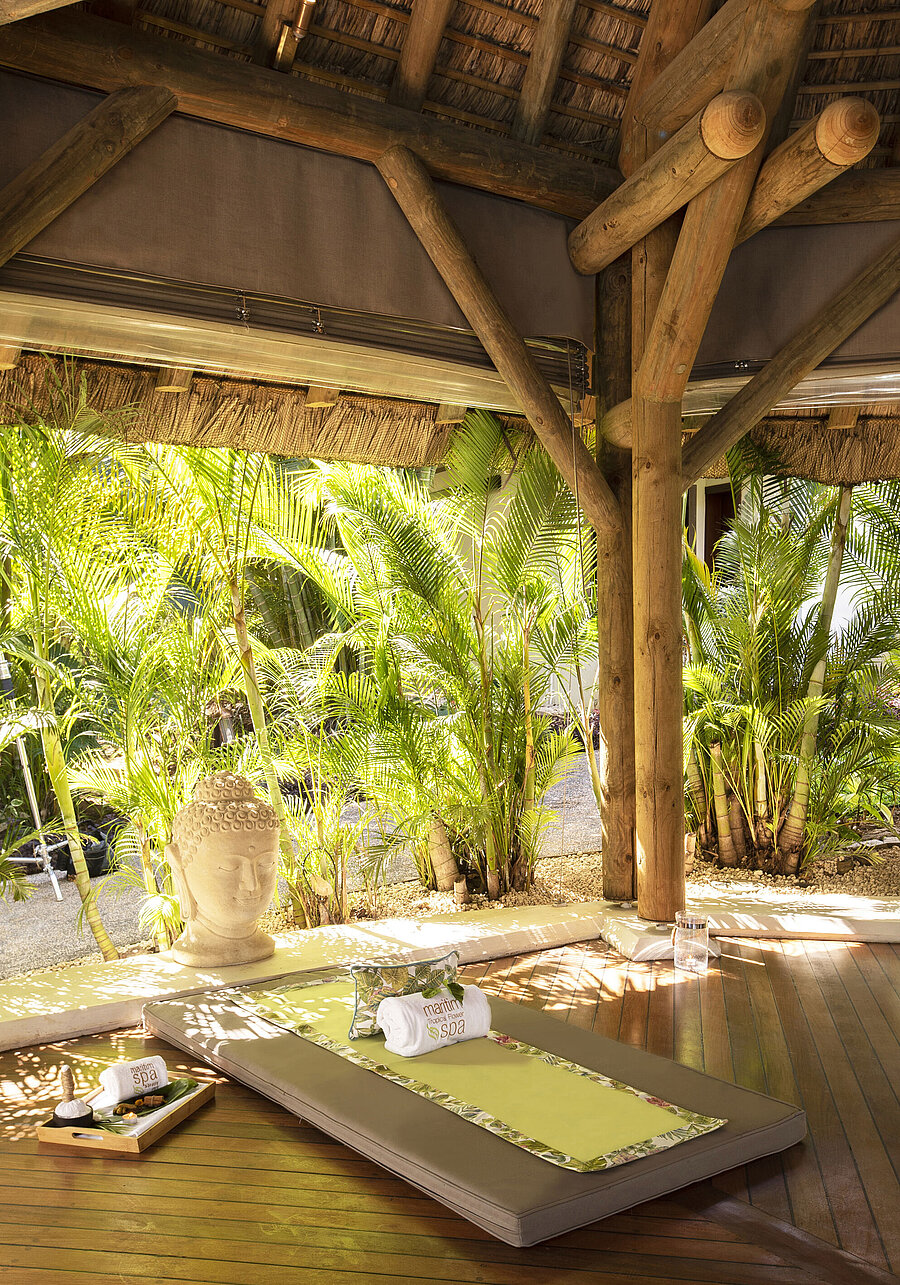 Spa Outdoor spa lounger in lush greenery with Buddha statue, wooden floor and tropical plants