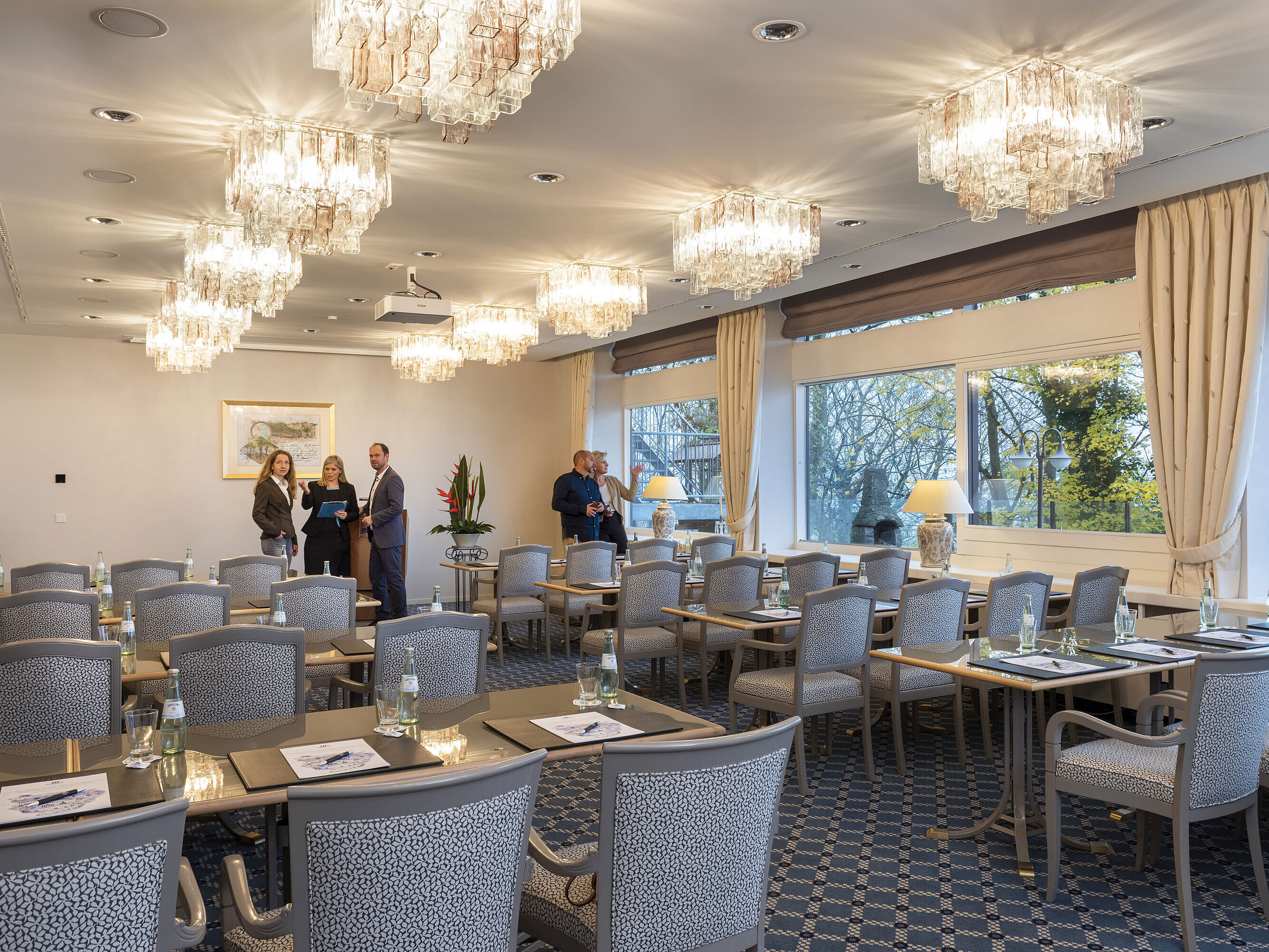 The Salon Copenhagen in the Maritim Hotel Kiel, an elegant conference room with chandeliers, laid tables and large windows.