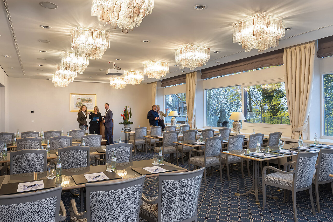 The Salon Copenhagen in the Maritim Hotel Kiel, an elegant conference room with chandeliers, laid tables and large windows.