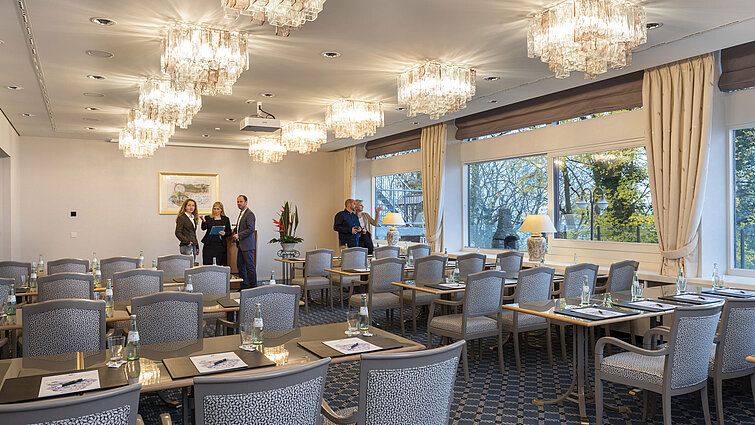 The Salon Copenhagen in the Maritim Hotel Kiel, an elegant conference room with chandeliers, laid tables and large windows.