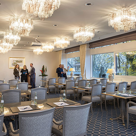 The Salon Copenhagen in the Maritim Hotel Kiel, an elegant conference room with chandeliers, laid tables and large windows.