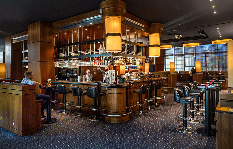 Stylish hotel bar at Maritim Hotel Düsseldorf with modern design, cozy atmosphere, and guests at the bar.