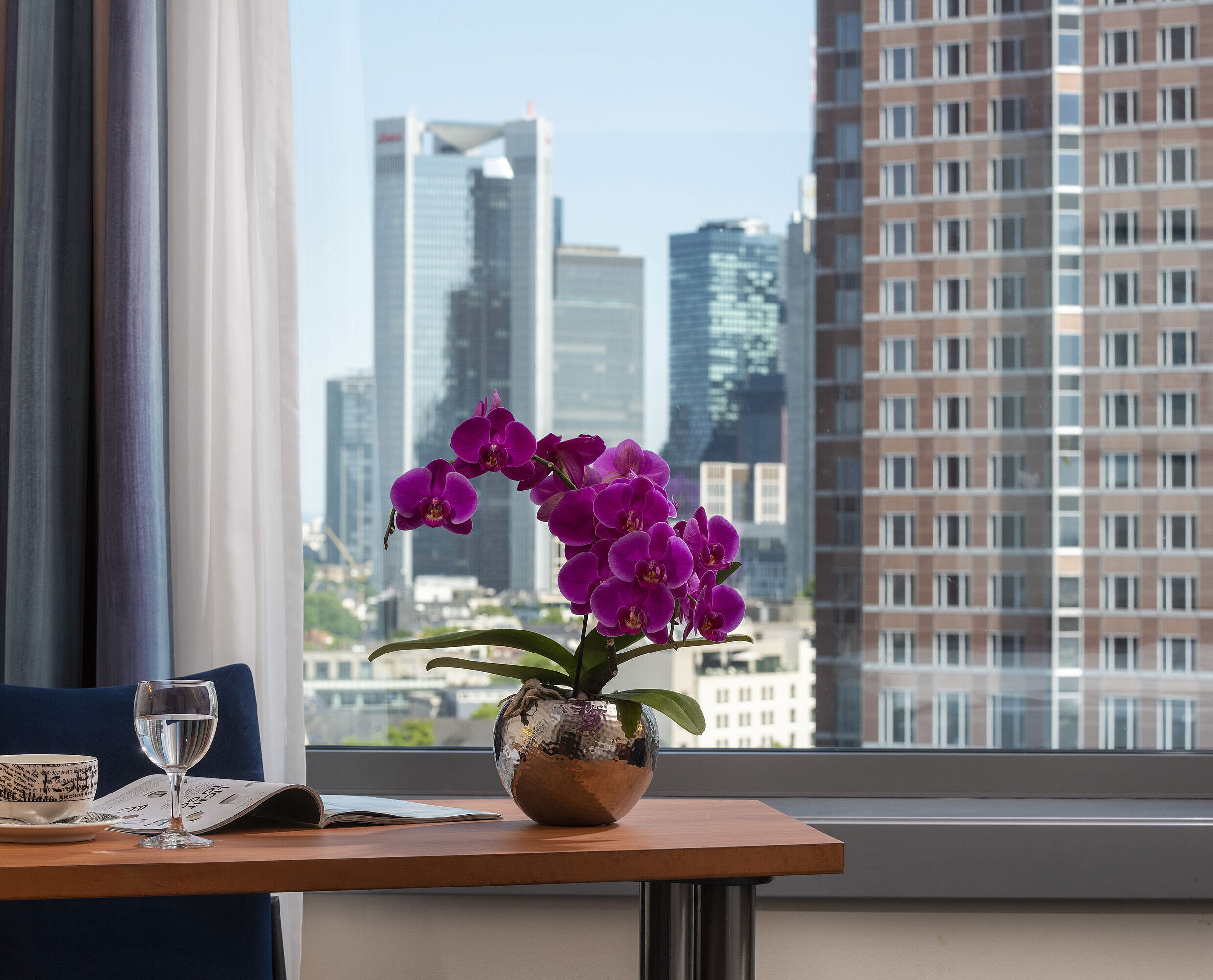 View from the room at Maritim Hotel Frankfurt with skyline panorama, desk, and elegant orchid.