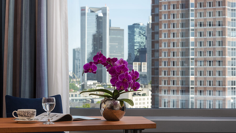 View from the room at Maritim Hotel Frankfurt with skyline panorama, desk, and elegant orchid.