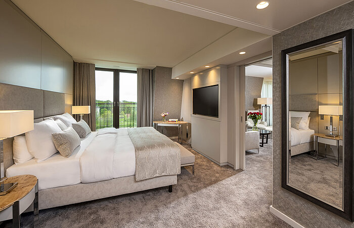 Elegant bedroom with a large bed, stylish interior, and floor-to-ceiling windows with a view at Maritim Hotel Ingolstadt.