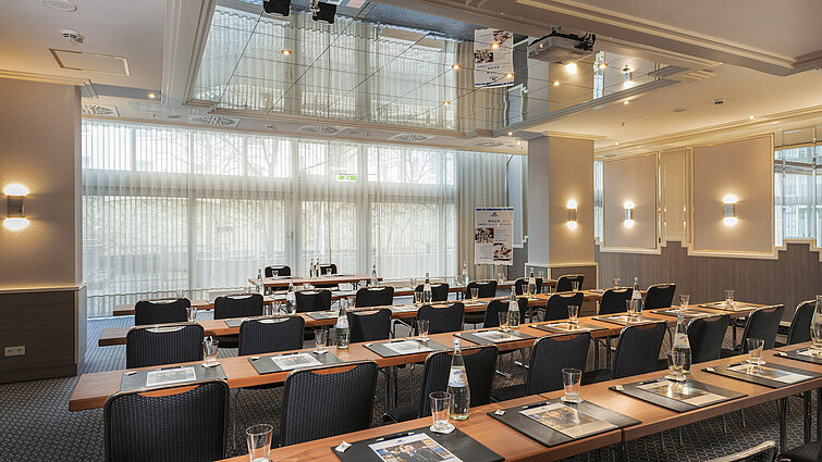 Meeting room with large windows, tables and water bottles at the Maritim Hotel Munich