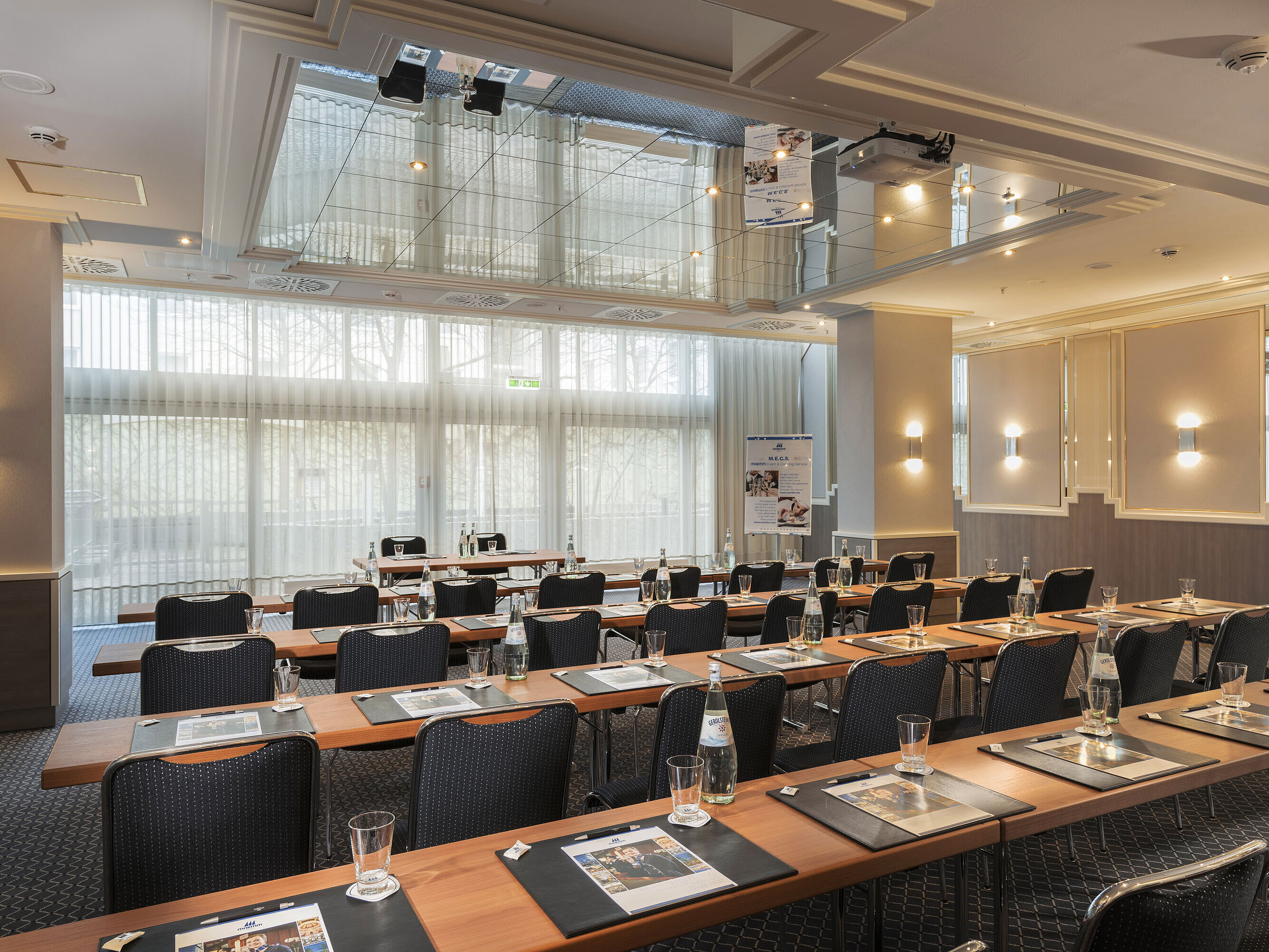 Meeting room with large windows, tables and water bottles at the Maritim Hotel Munich