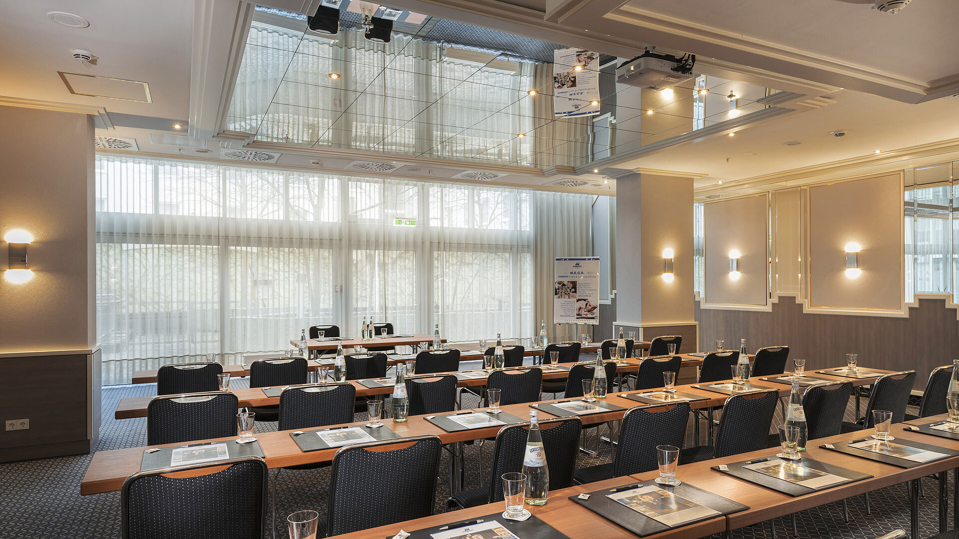 Meeting room with large windows, tables and water bottles at the Maritim Hotel Munich