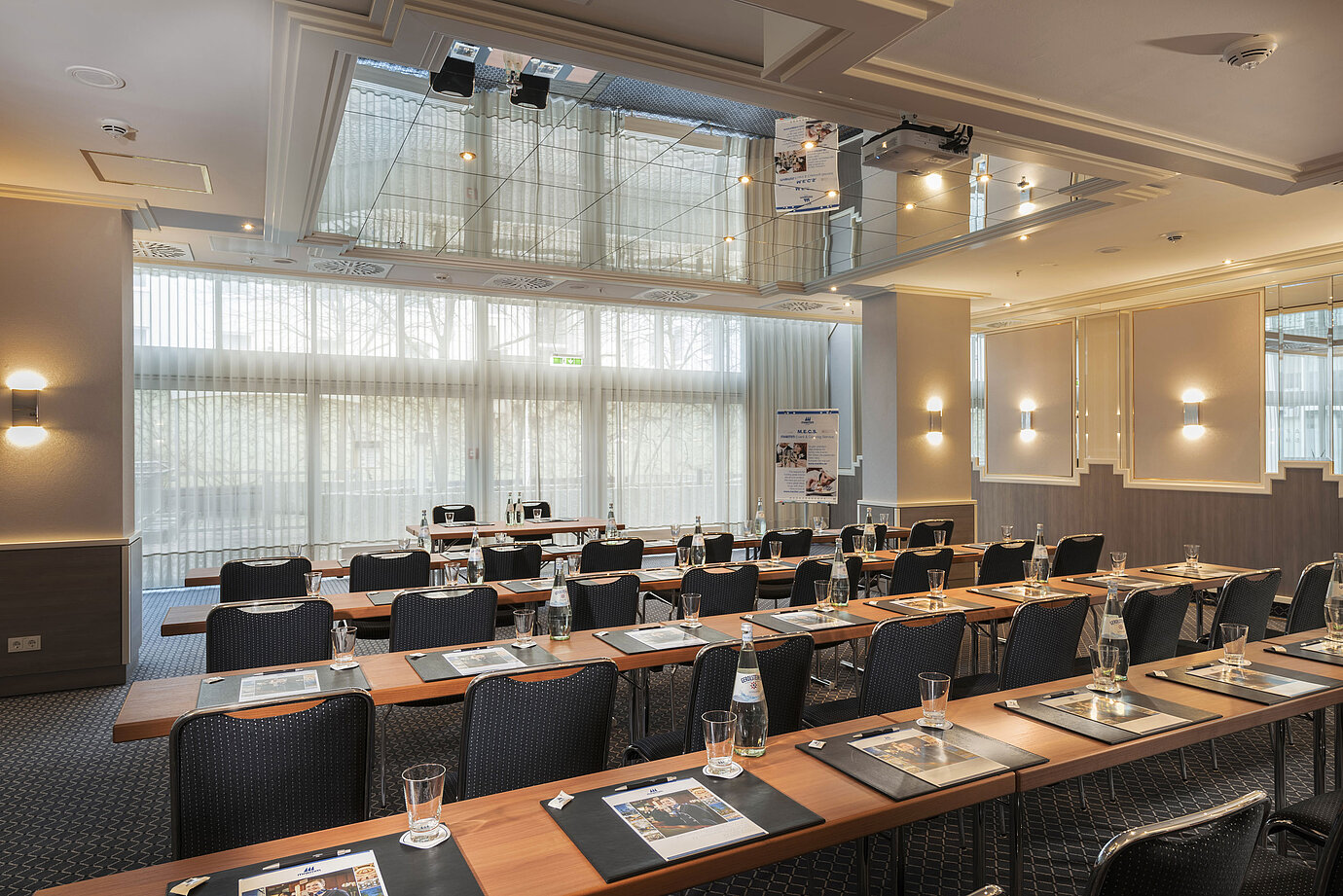 Meeting room with large windows, tables and water bottles at the Maritim Hotel Munich