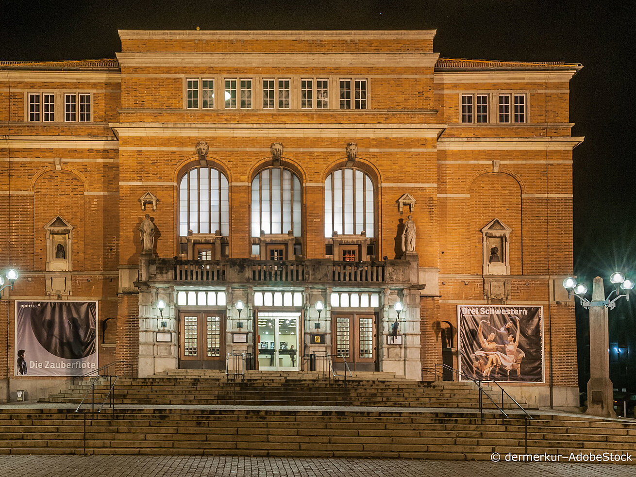 Illuminated facade of Kiel Opera House at night showcasing historic architecture and grand staircase