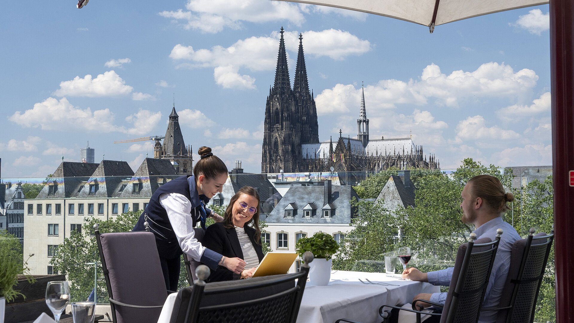 Guests enjoying service on the rooftop terrace of Maritim Hotel Cologne with views of Cologne Cathedral and the Old Town.