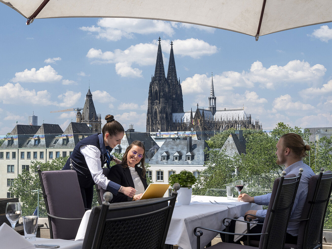 Guests enjoying service on the rooftop terrace of Maritim Hotel Cologne with views of Cologne Cathedral and the Old Town.