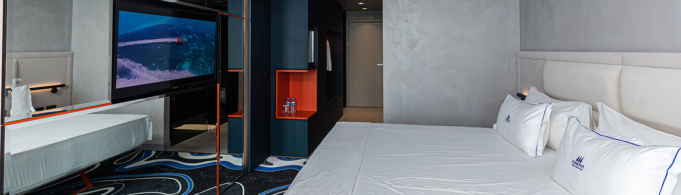 Spacious room at Maritim Resort Marina Bay with large mirror, TV and double bed