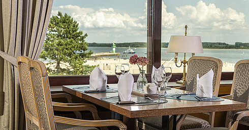 Set table by the window with view of beach and lighthouse at Maritim Hotel Travemünde
