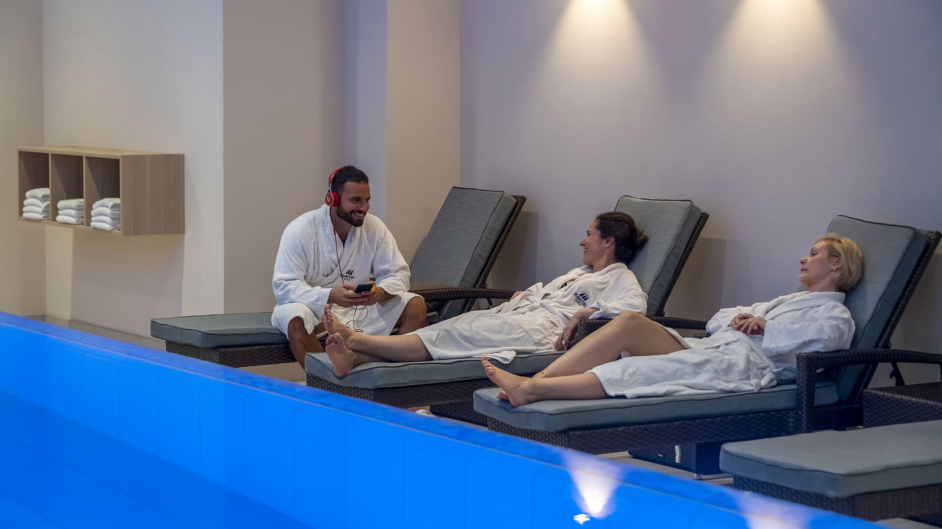 Guests relax on loungers by the pool at Maritim Hotel Ingolstadt in a tranquil atmosphere.
