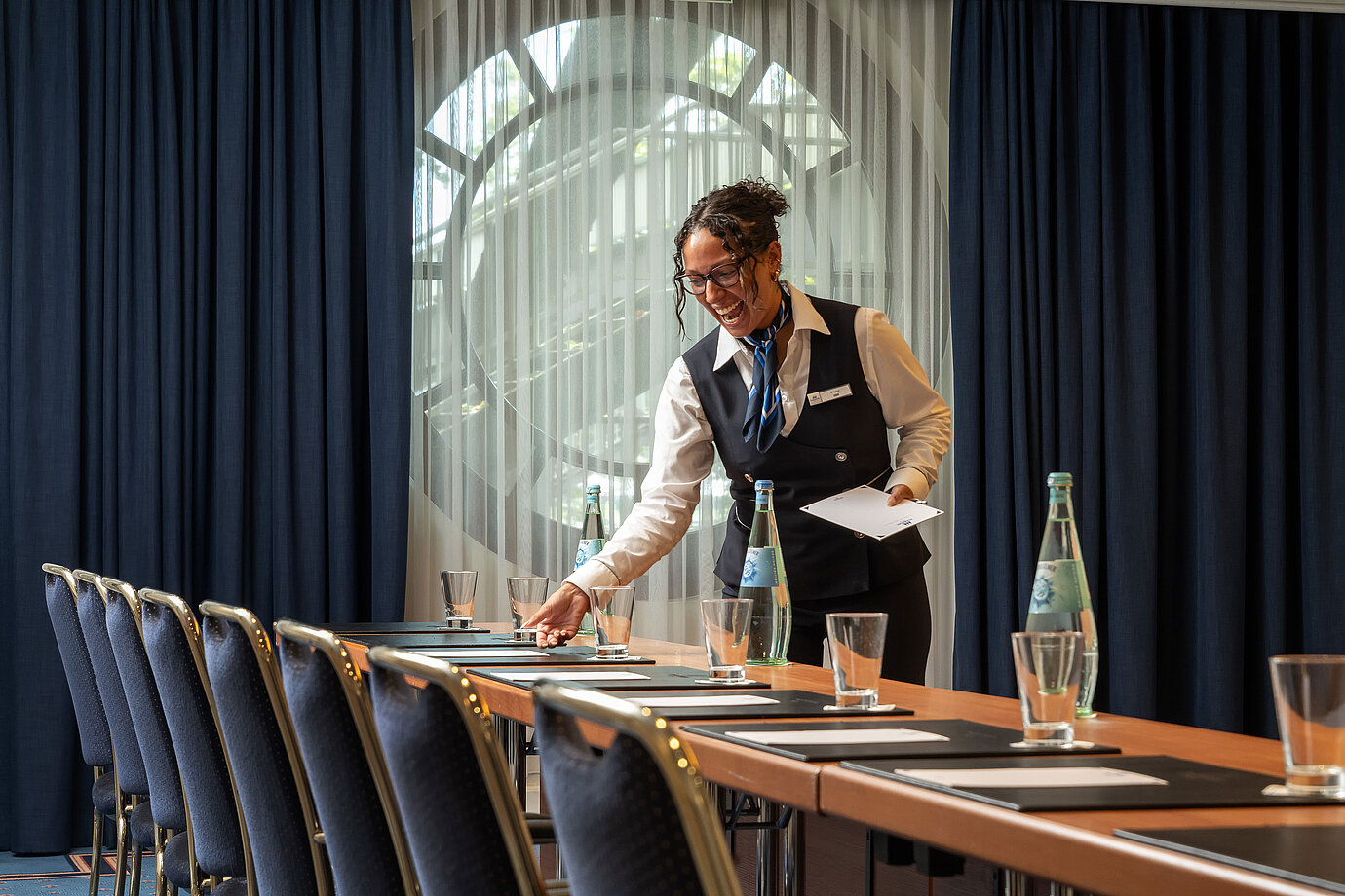 Staff member prepares conference room at Maritim Hotel Köln with a smile for guests