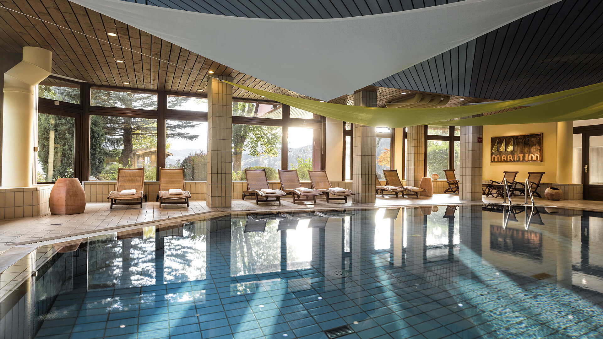 Bright indoor pool with loungers and garden view at the Maritim Hotel Titisee