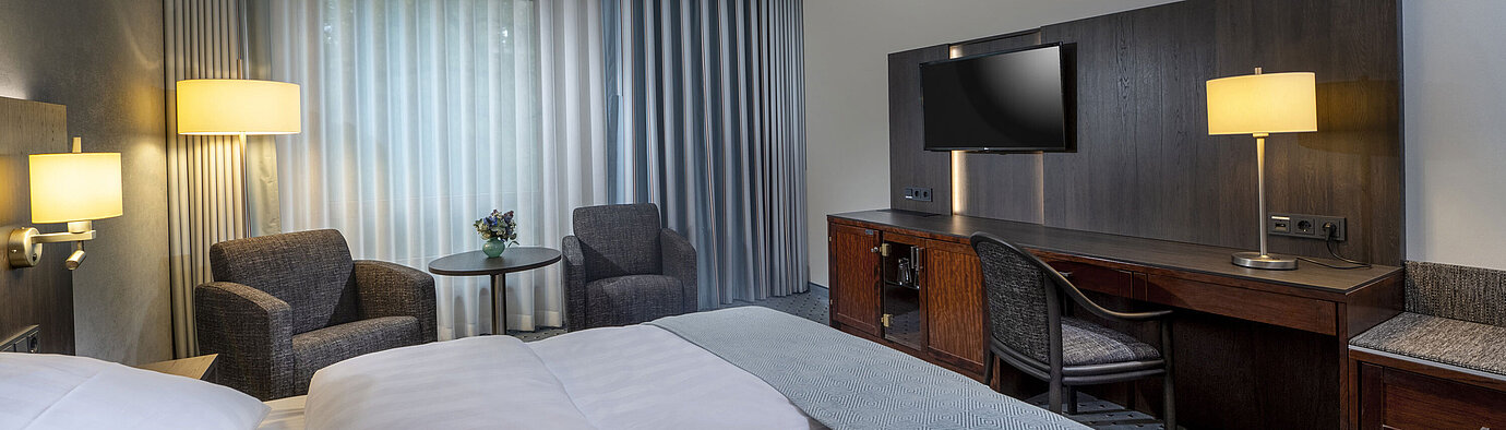 Modernly furnished Classic room with desk, TV, seating area, and comfortable bed at Maritim Hotel Bremen.