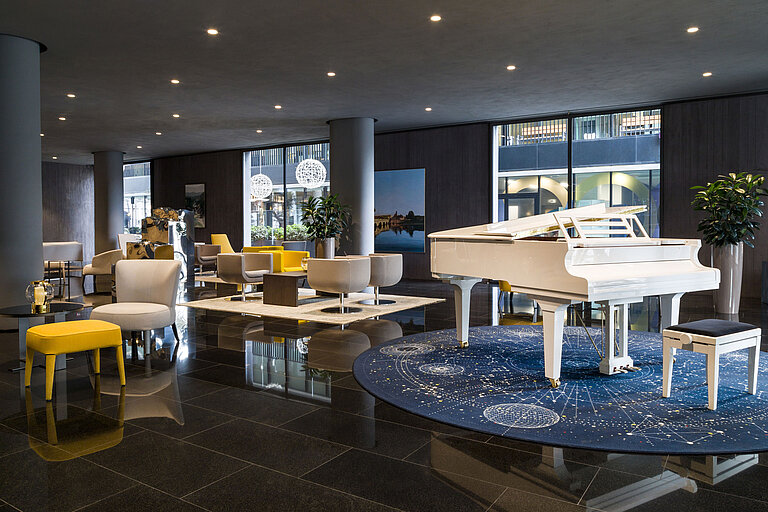 Stylish lobby with white grand piano and modern seating at Maritim Hotel Plaza Tirana