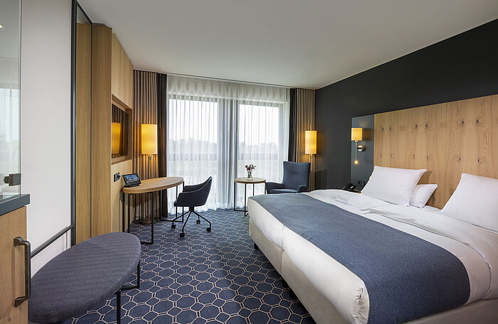 Spacious double room at Maritim Hotel Ingolstadt with desk, seating area, and balcony.