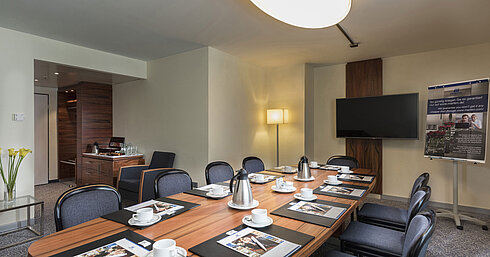 Meeting room with wooden table, chairs and presentation setup at the Maritim Hotel Munich