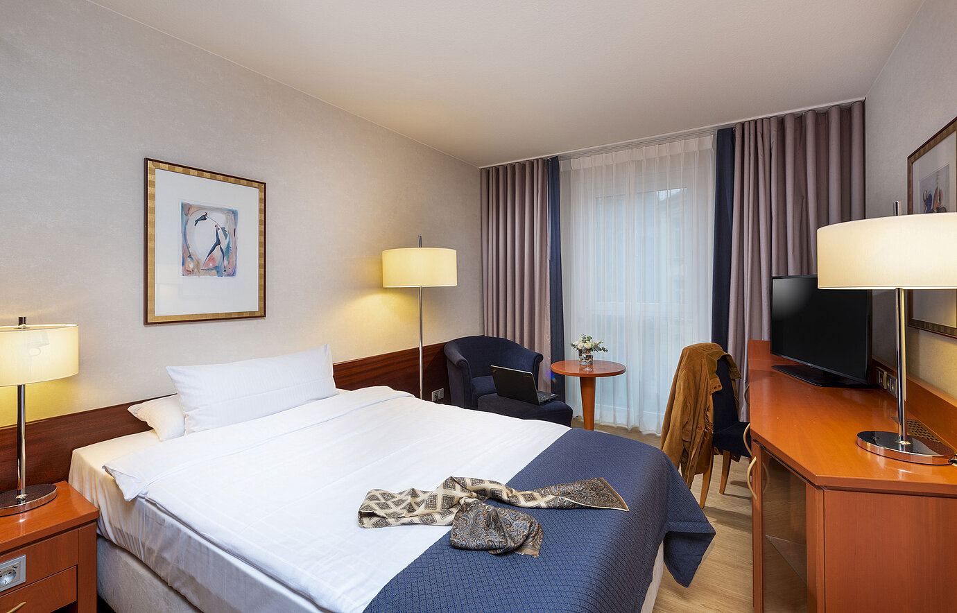 Bright single room at Maritim Hotel Würzburg with seating area and modern wardrobe