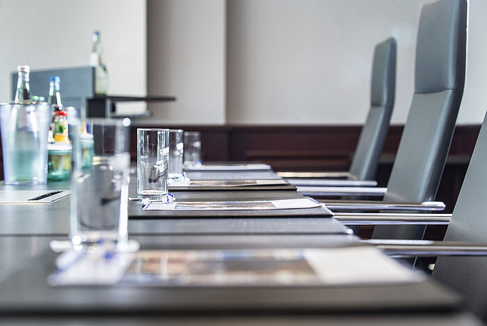 Close-up of a stylishly set conference table with glasses and writing pads at Maritim Hotel Hannover.