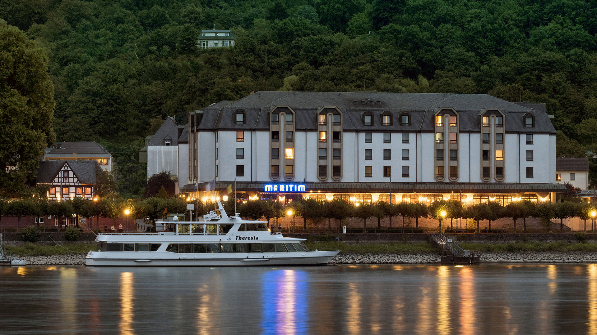 Maritim Hotel Königswinter at night with atmospheric lighting and a view of the Rhine.